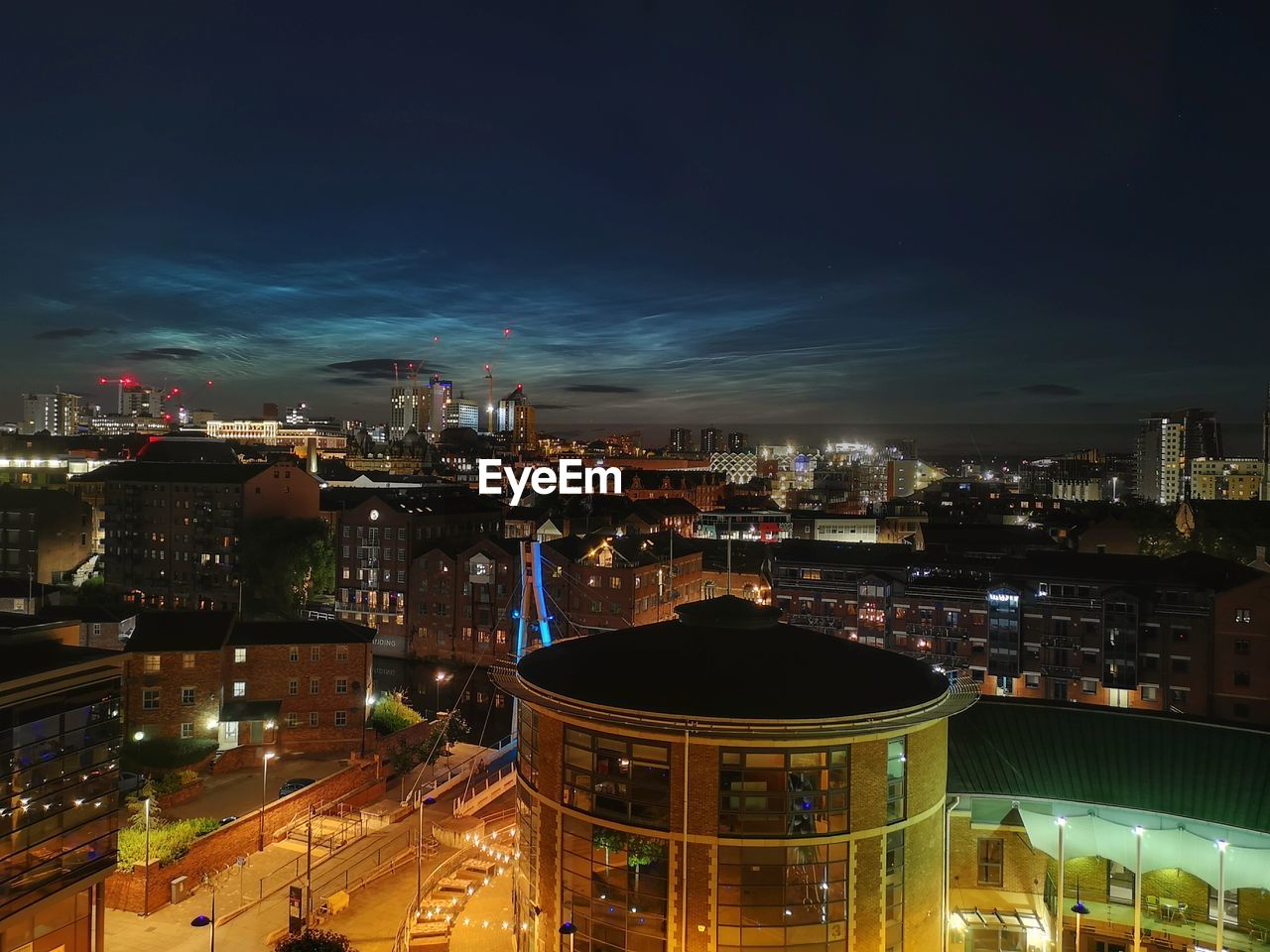 HIGH ANGLE VIEW OF ILLUMINATED CITY BUILDINGS AT NIGHT