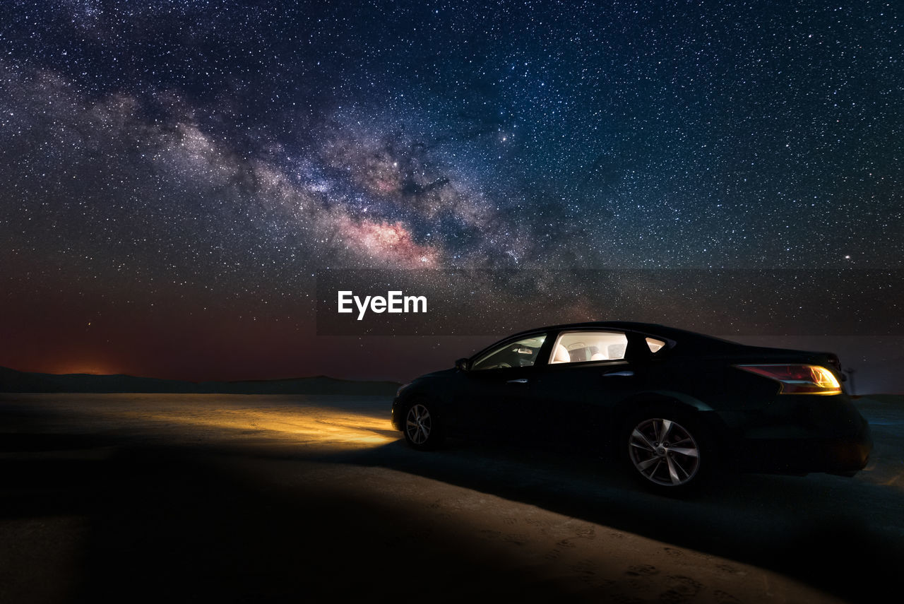 CAR ON ILLUMINATED STREET AGAINST STAR FIELD