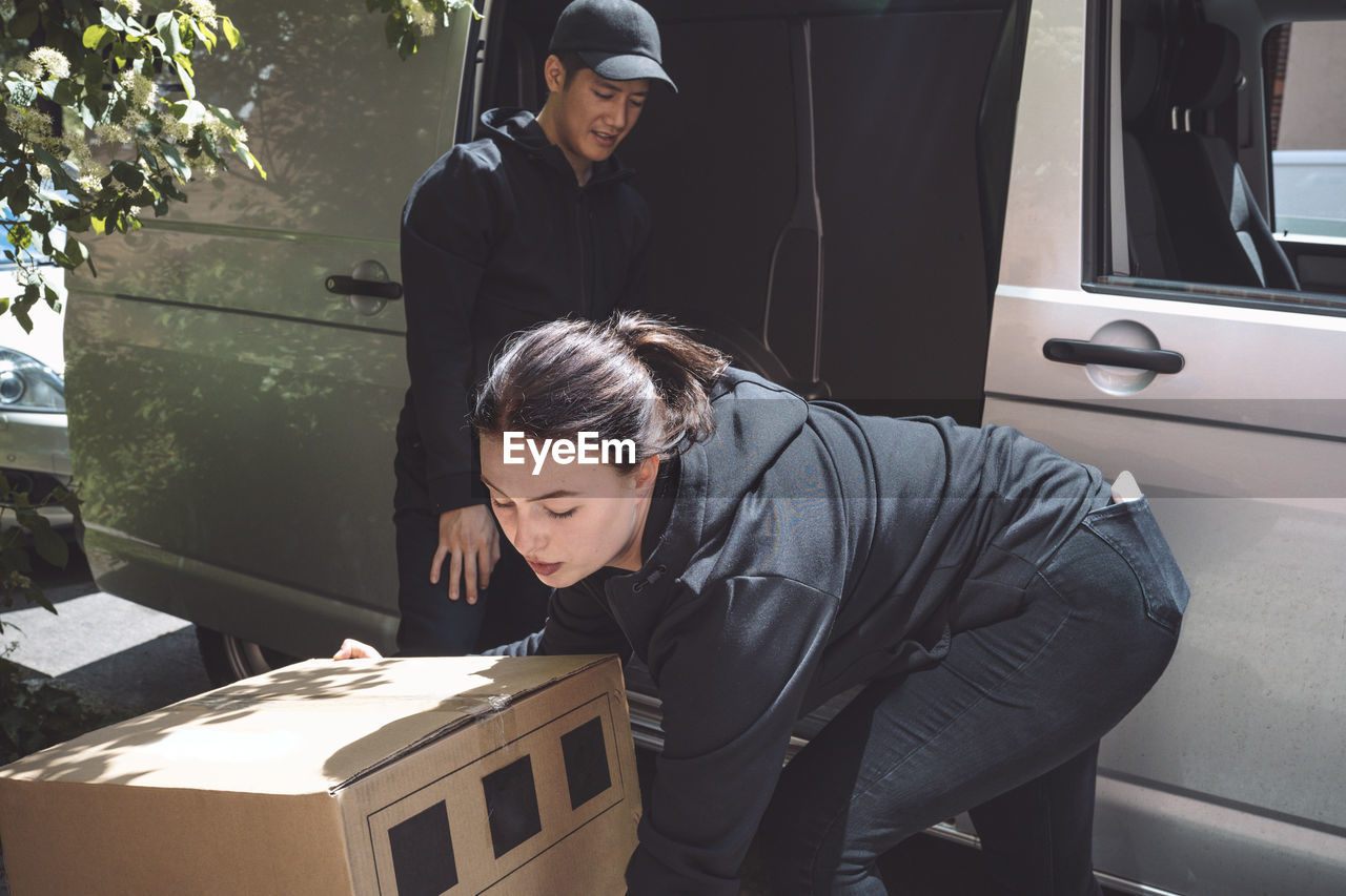 Male and female delivery workers arranging package outside truck