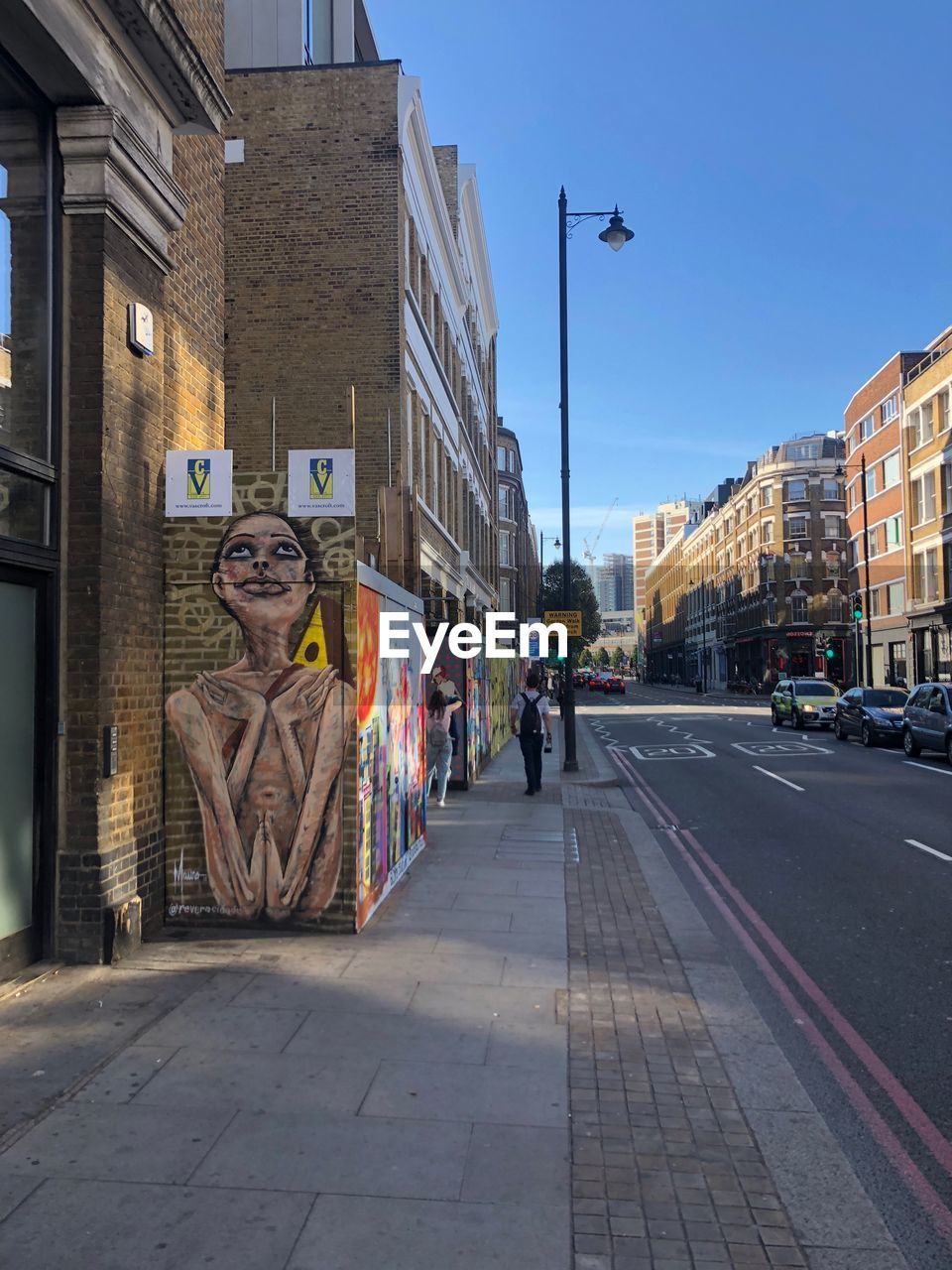 GRAFFITI ON CITY STREET BY BUILDINGS AGAINST SKY IN BACKGROUND