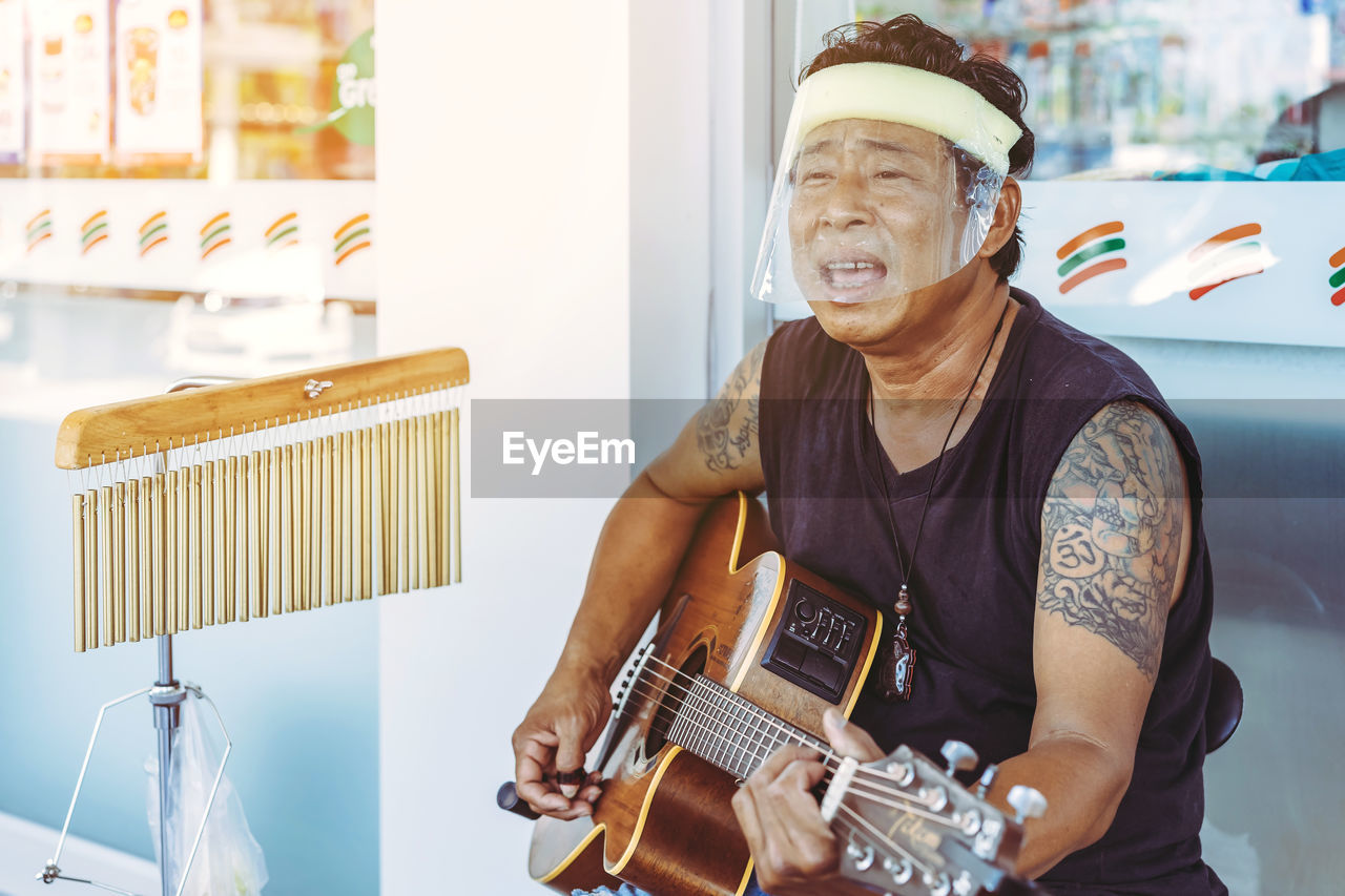 MID ADULT MAN PLAYING GUITAR AT HOME