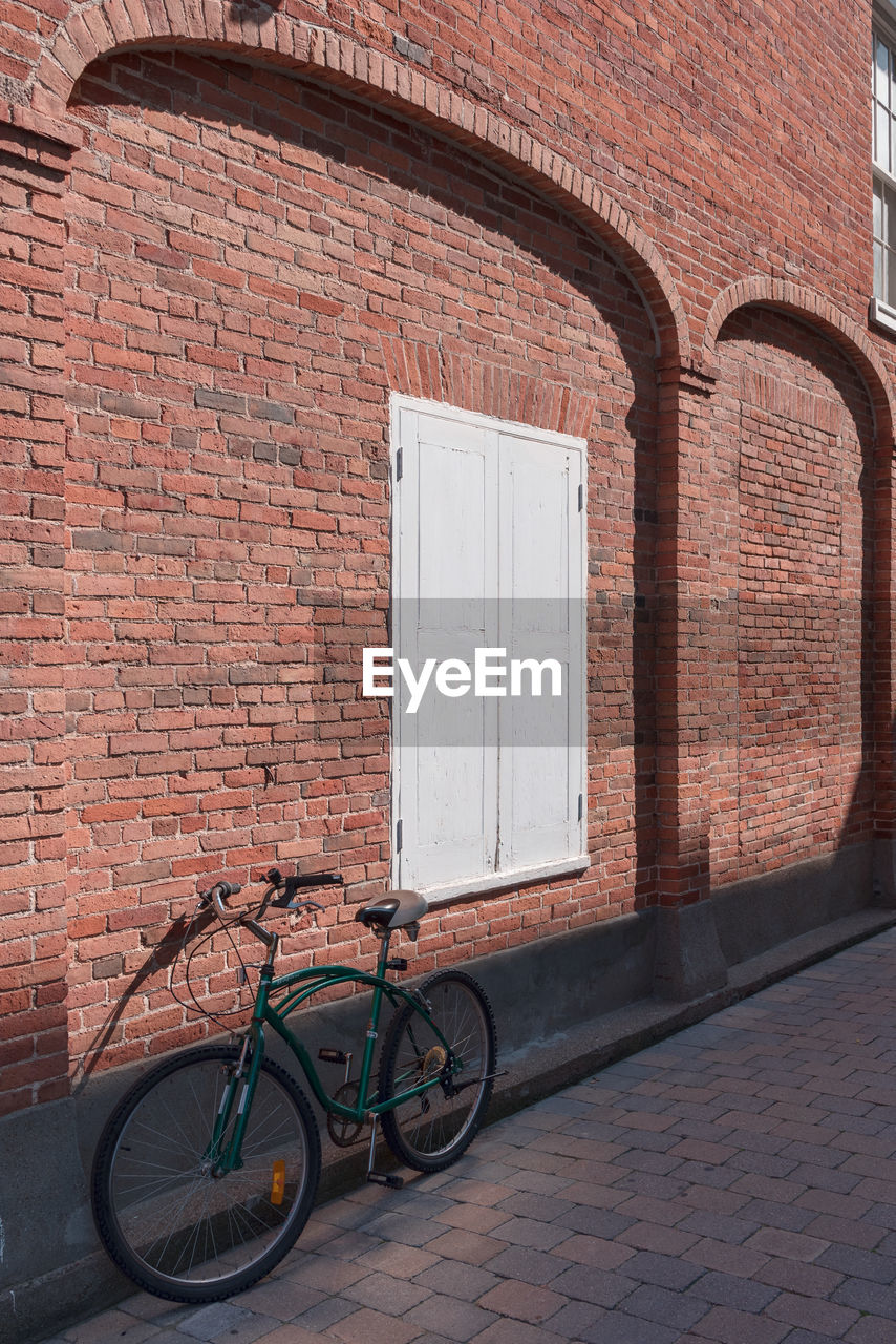 Bicycle parked against brick wall