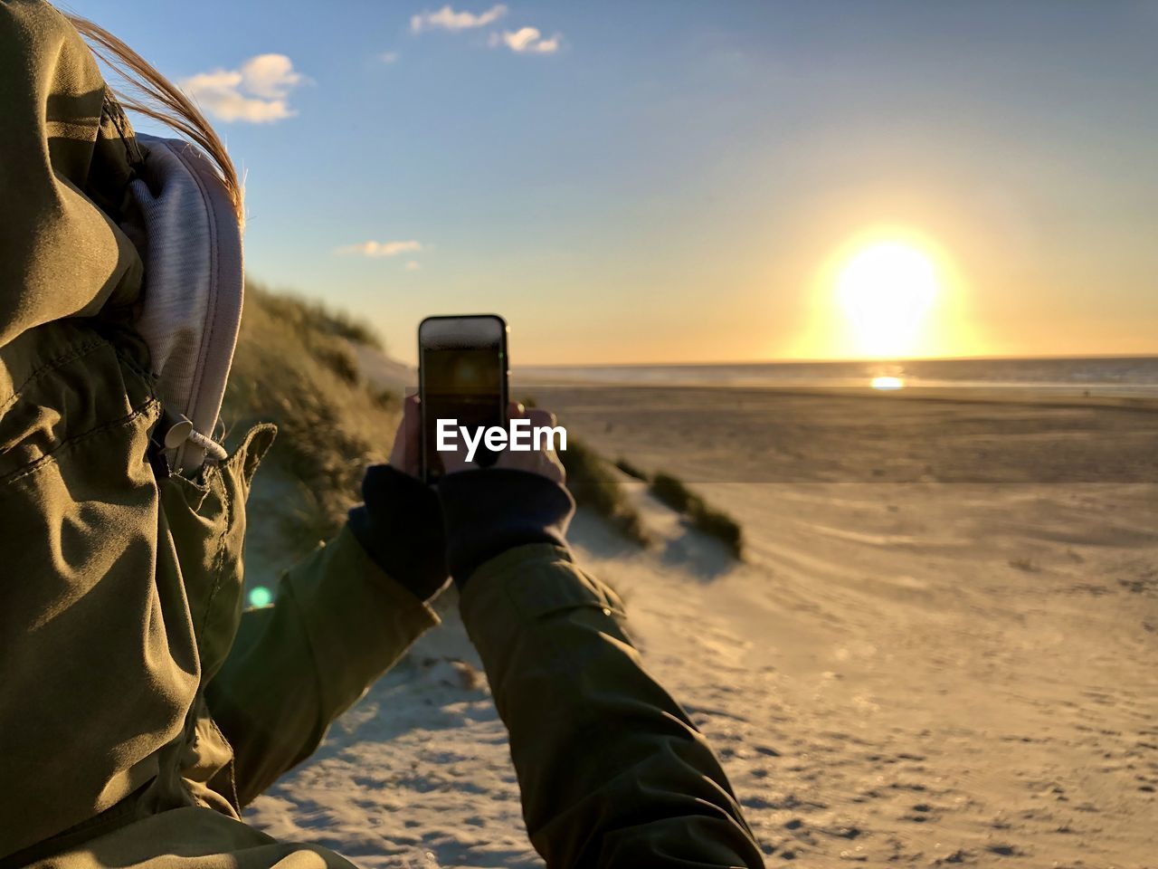 Man photographing at beach during sunset