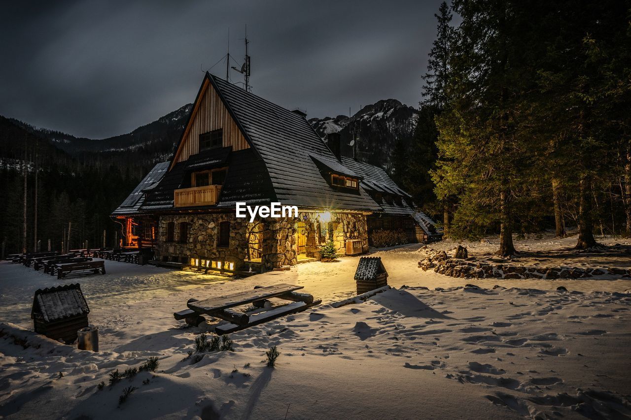 SNOW COVERED HOUSES BY BUILDINGS AGAINST SKY