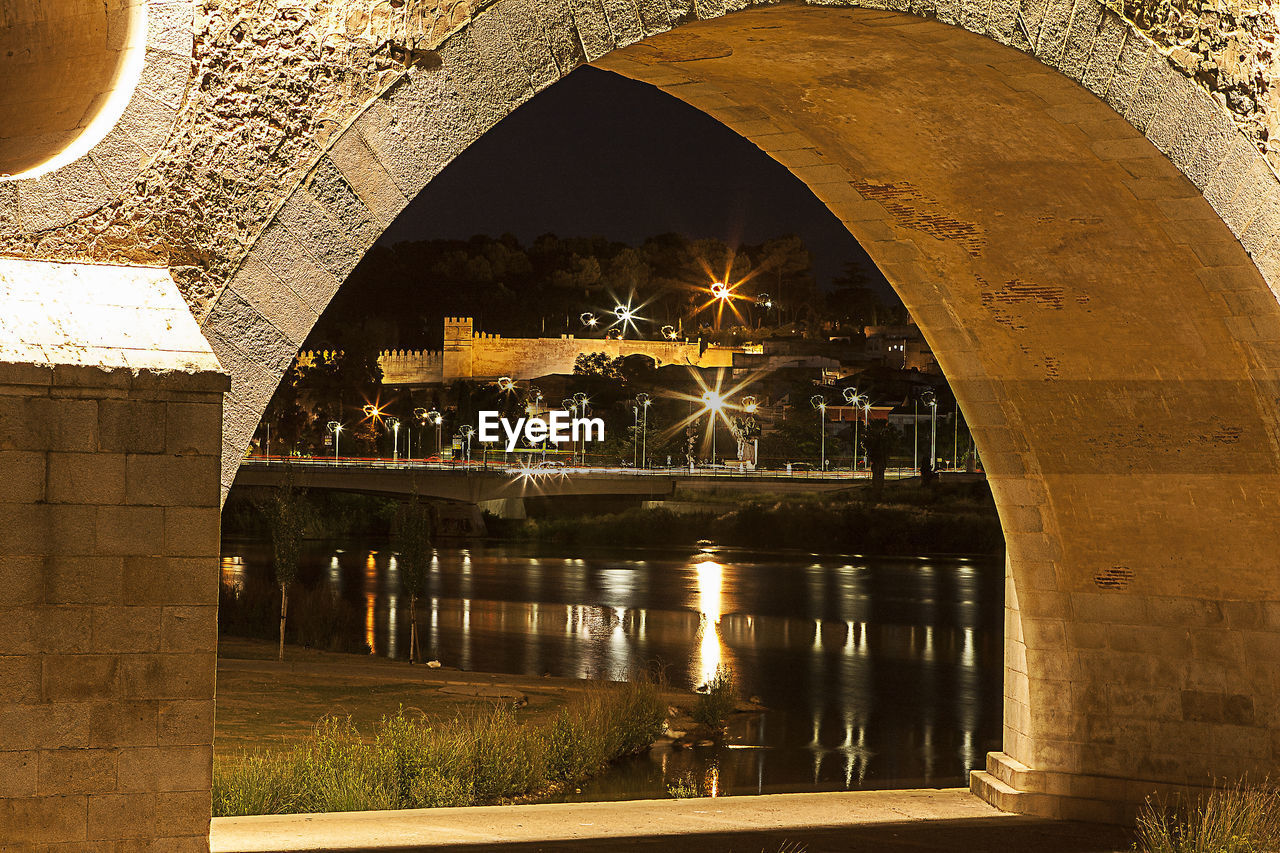 REFLECTION OF ILLUMINATED BRIDGE ON WATER IN MIRROR