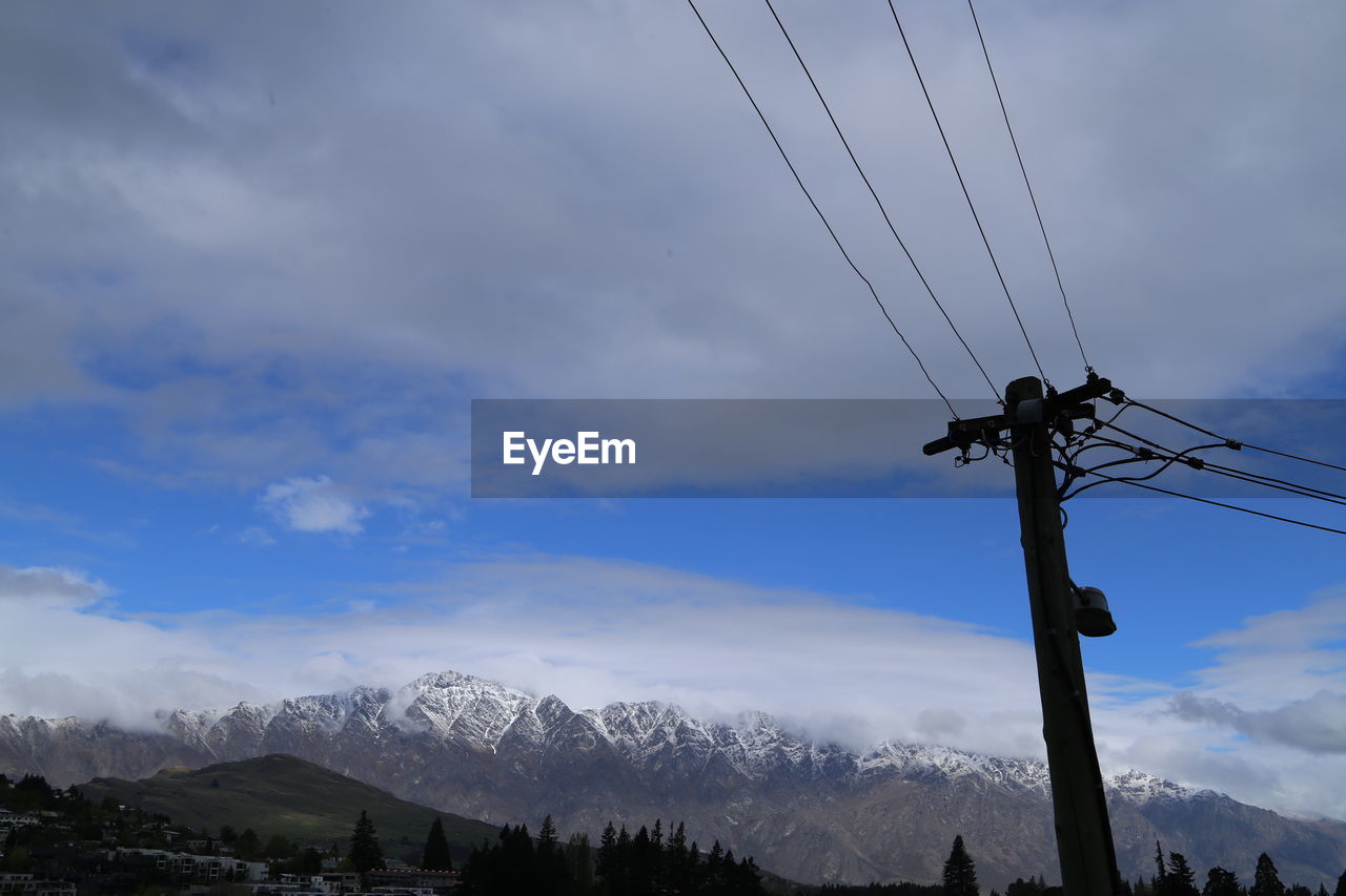 Low angle view of electricity pylon against sky during winter