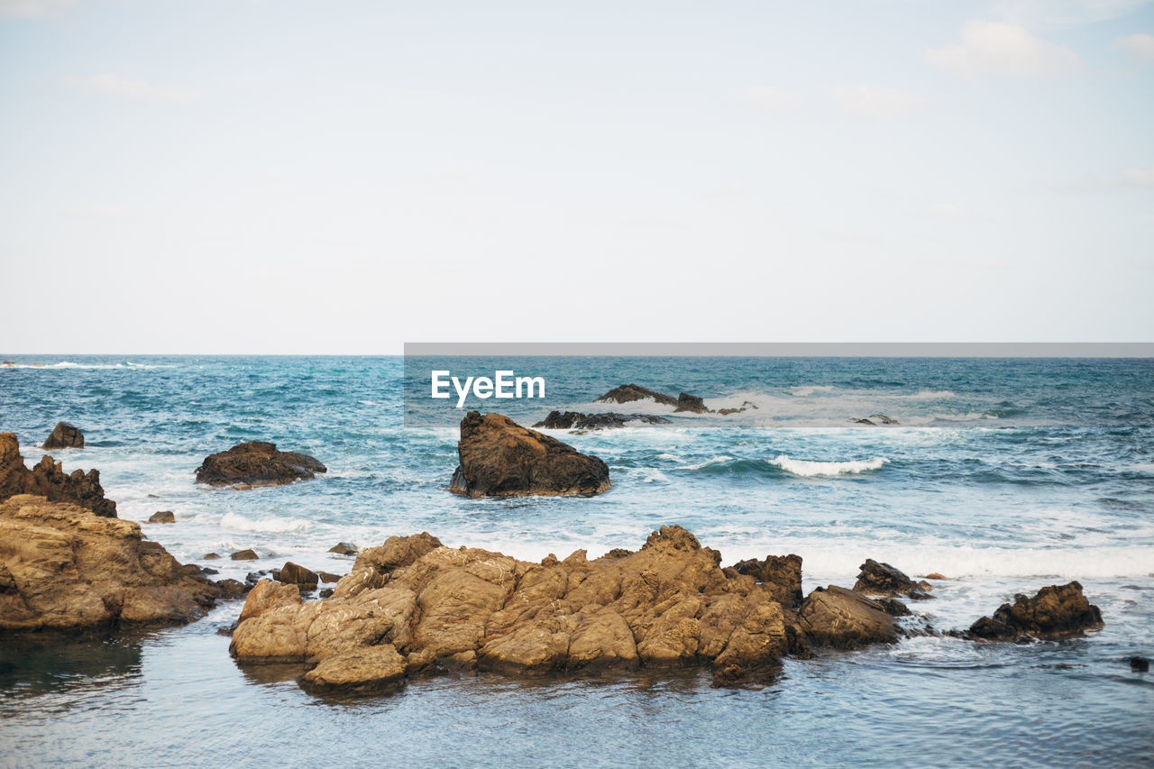 ROCKS ON SEA AGAINST SKY