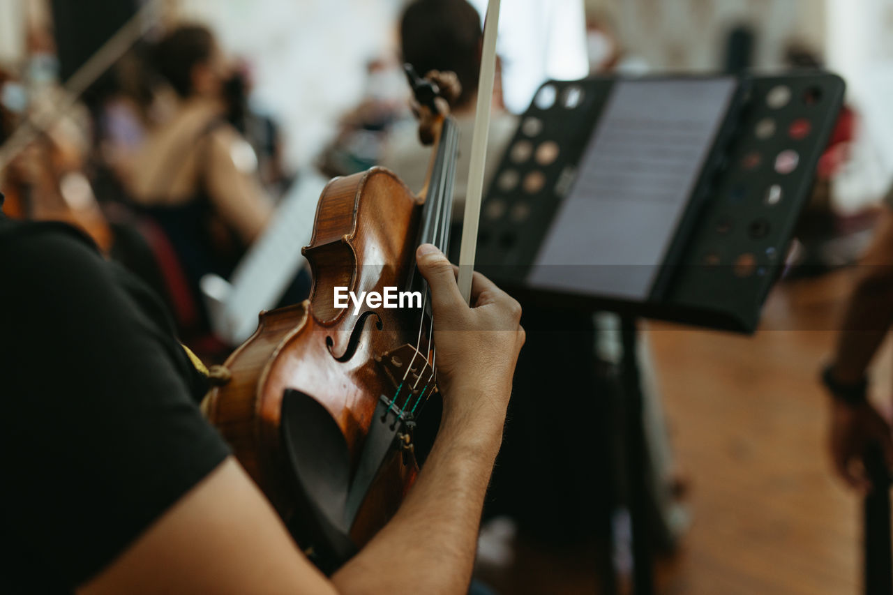 MIDSECTION OF MAN PLAYING GUITAR AT MUSIC