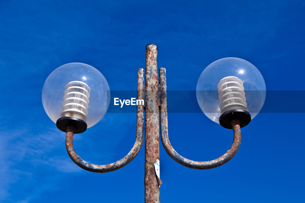 Low angle view of illuminated street light against blue sky