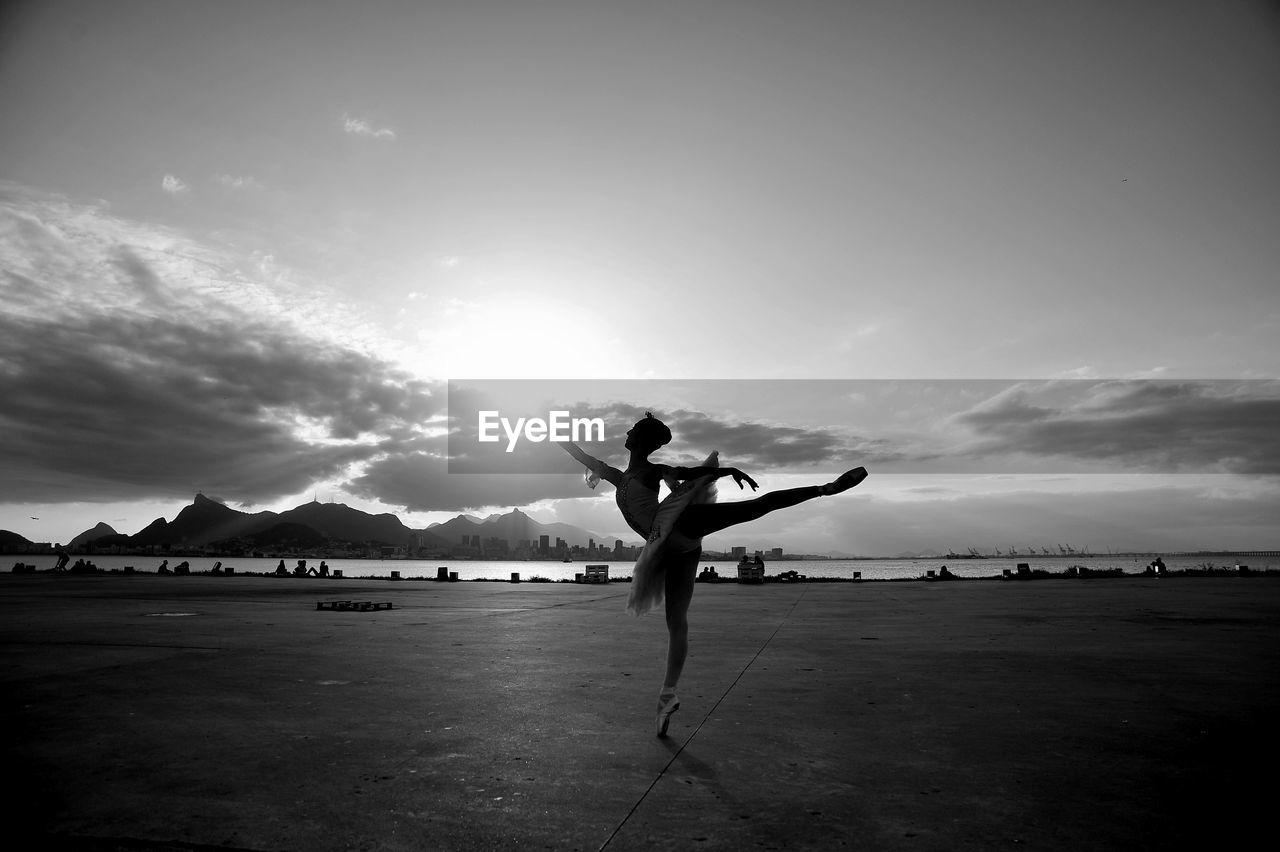 Full length of ballet dancer practicing against sky