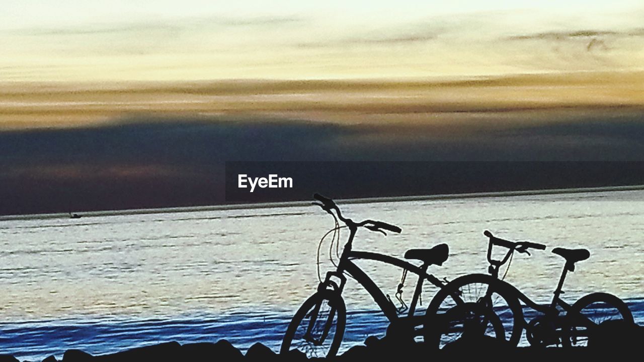 CLOSE-UP OF BICYCLE AGAINST SEA AT SUNSET