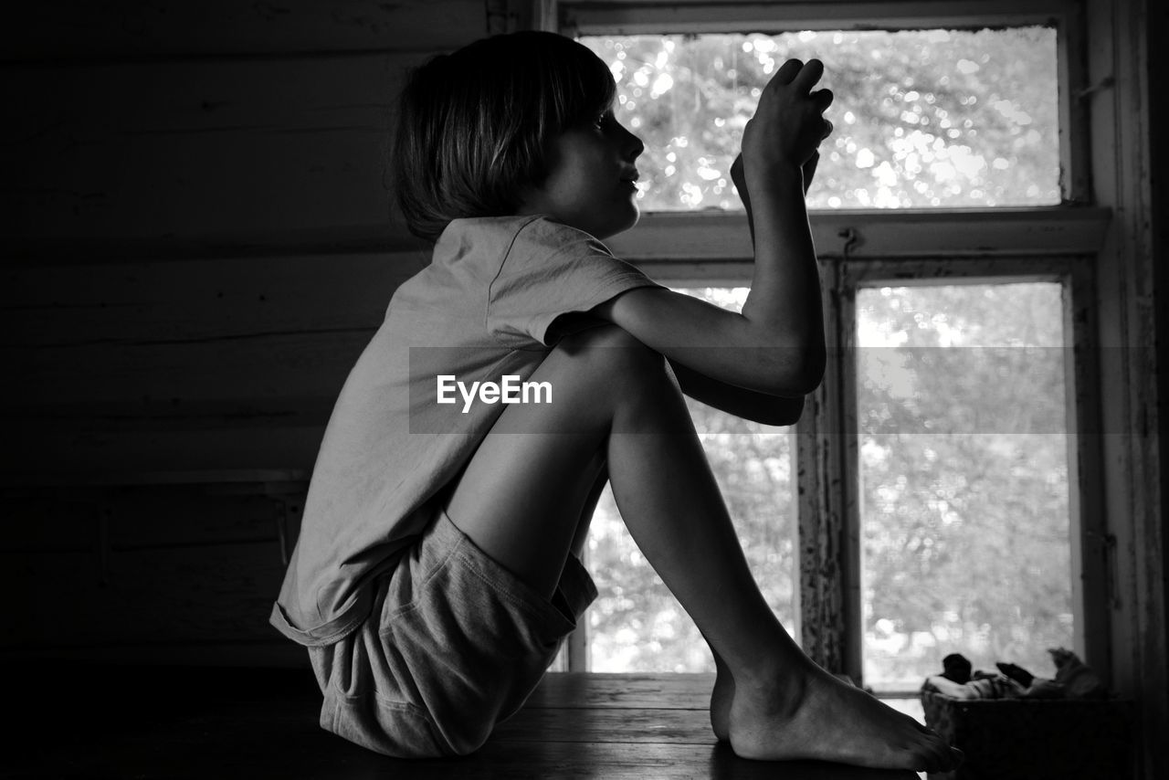 Side view of boy sitting at home