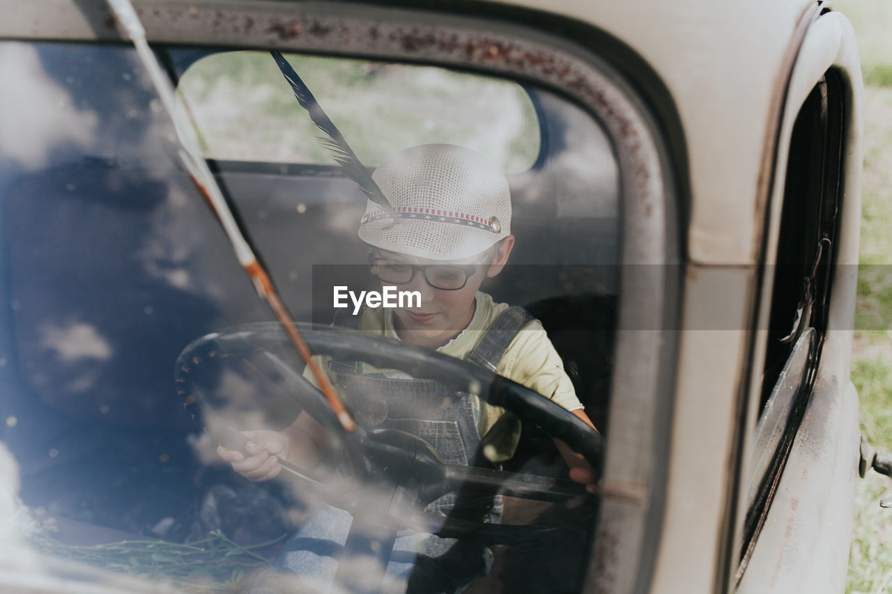 Boy holding steering wheel sitting in car