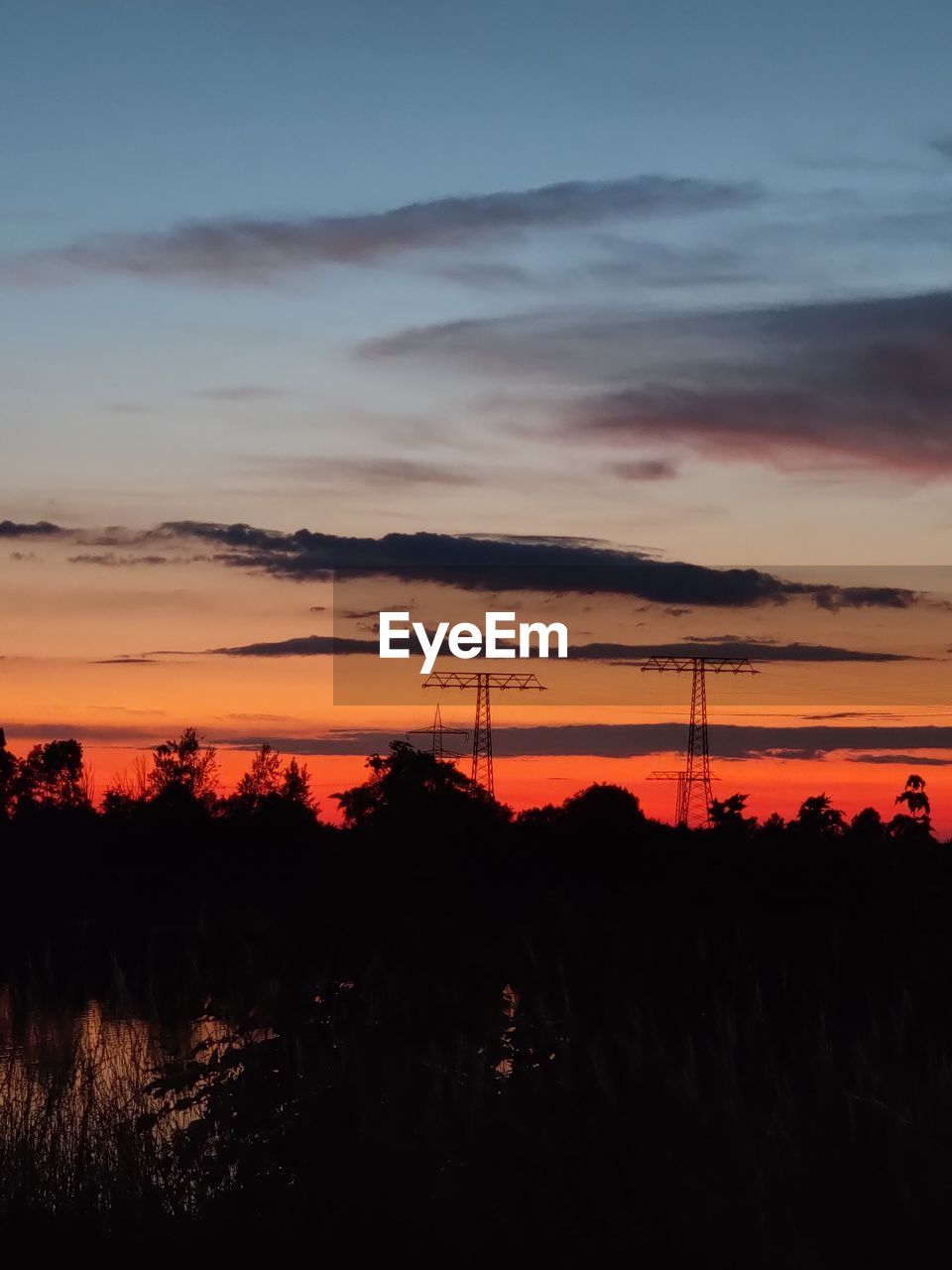 Silhouette landscape against dramatic sky during sunset