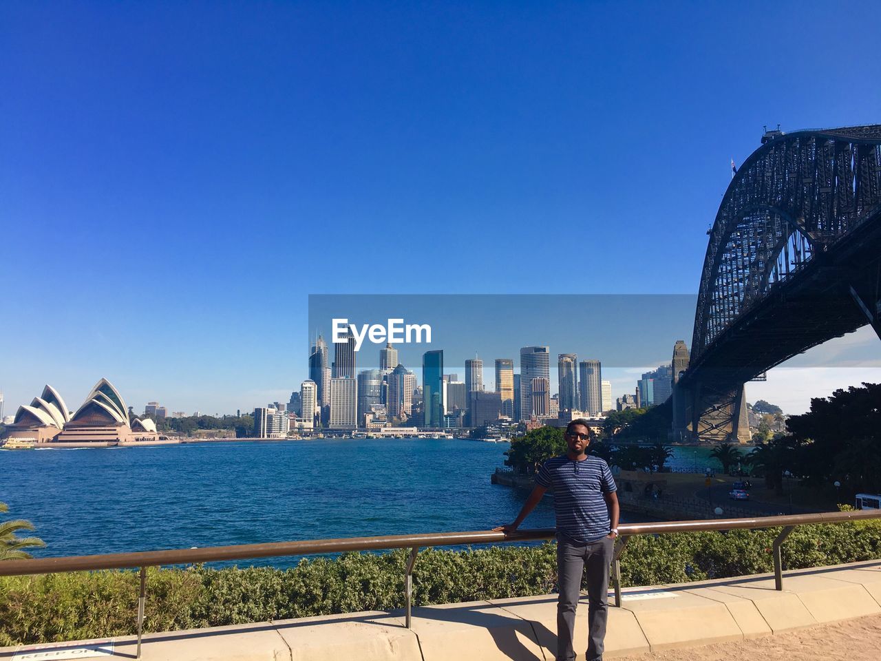 REAR VIEW OF MAN WITH WOMAN STANDING ON BRIDGE