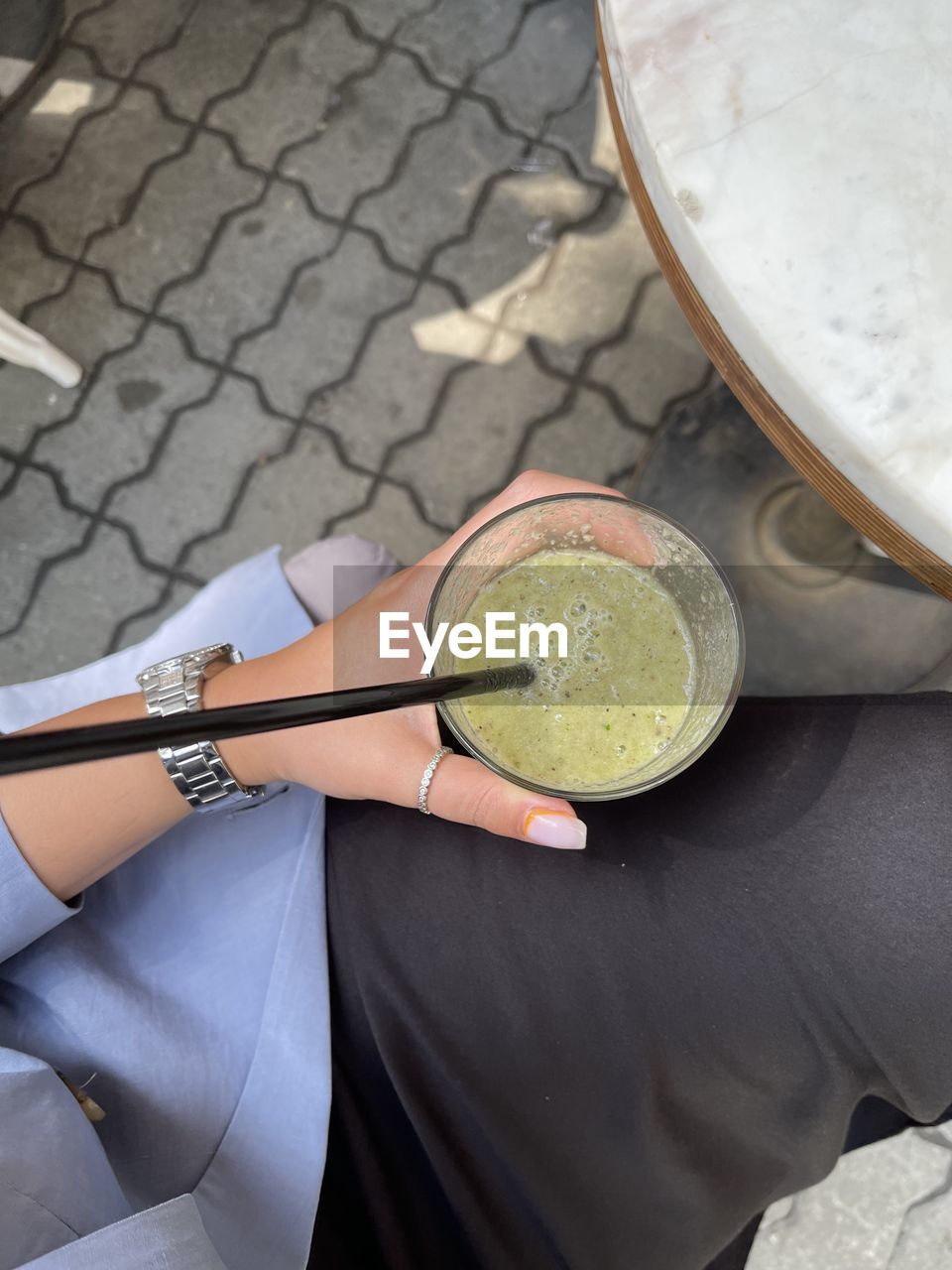 HIGH ANGLE VIEW OF WOMAN HAND HOLDING GLASS OF DRINK