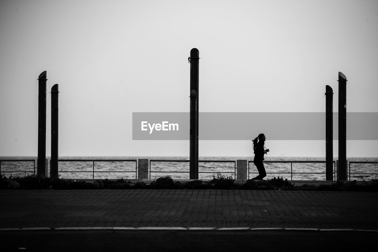 Woman jogging on promenade against sky