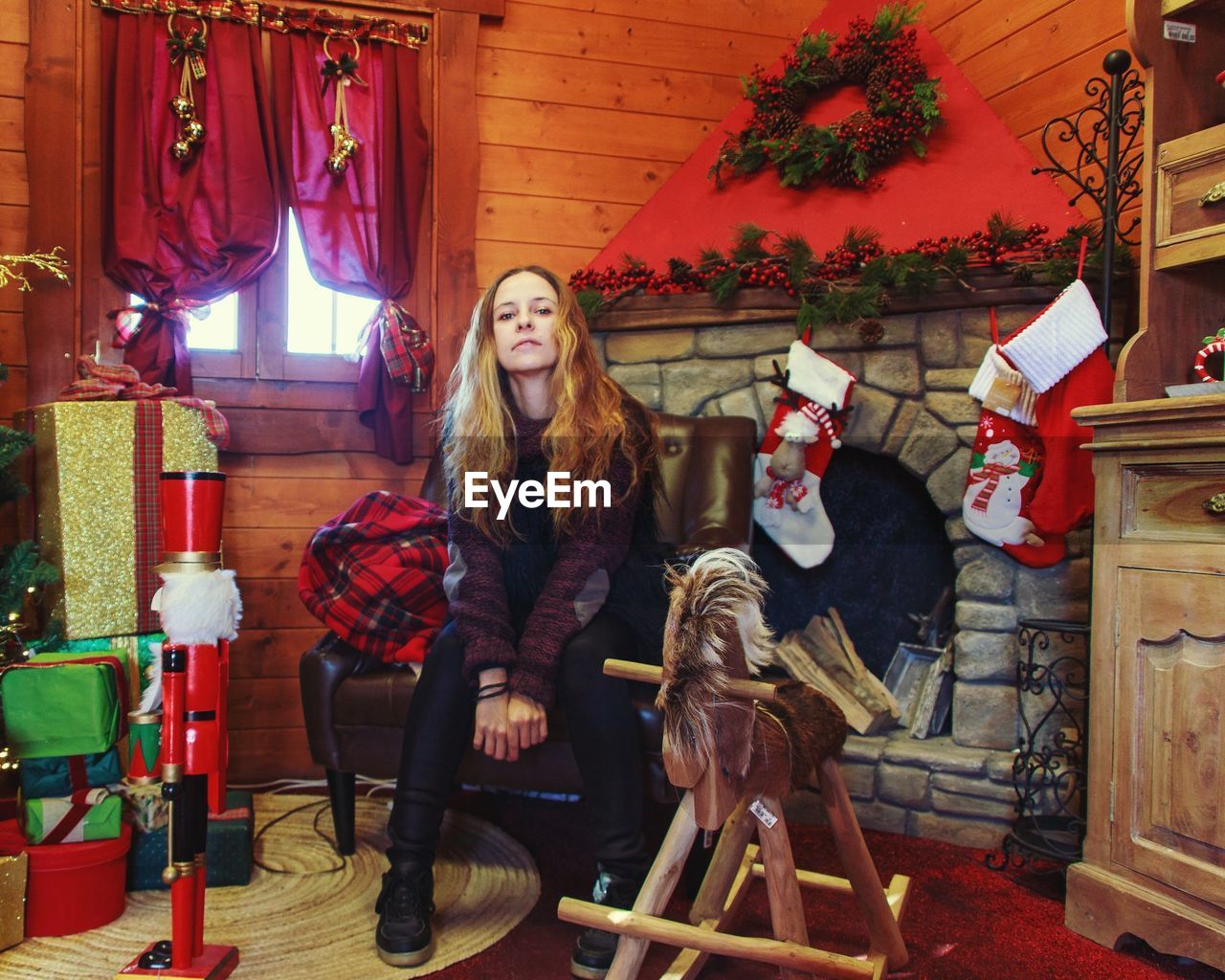 Full length portrait of woman sitting on chair at home during christmas 