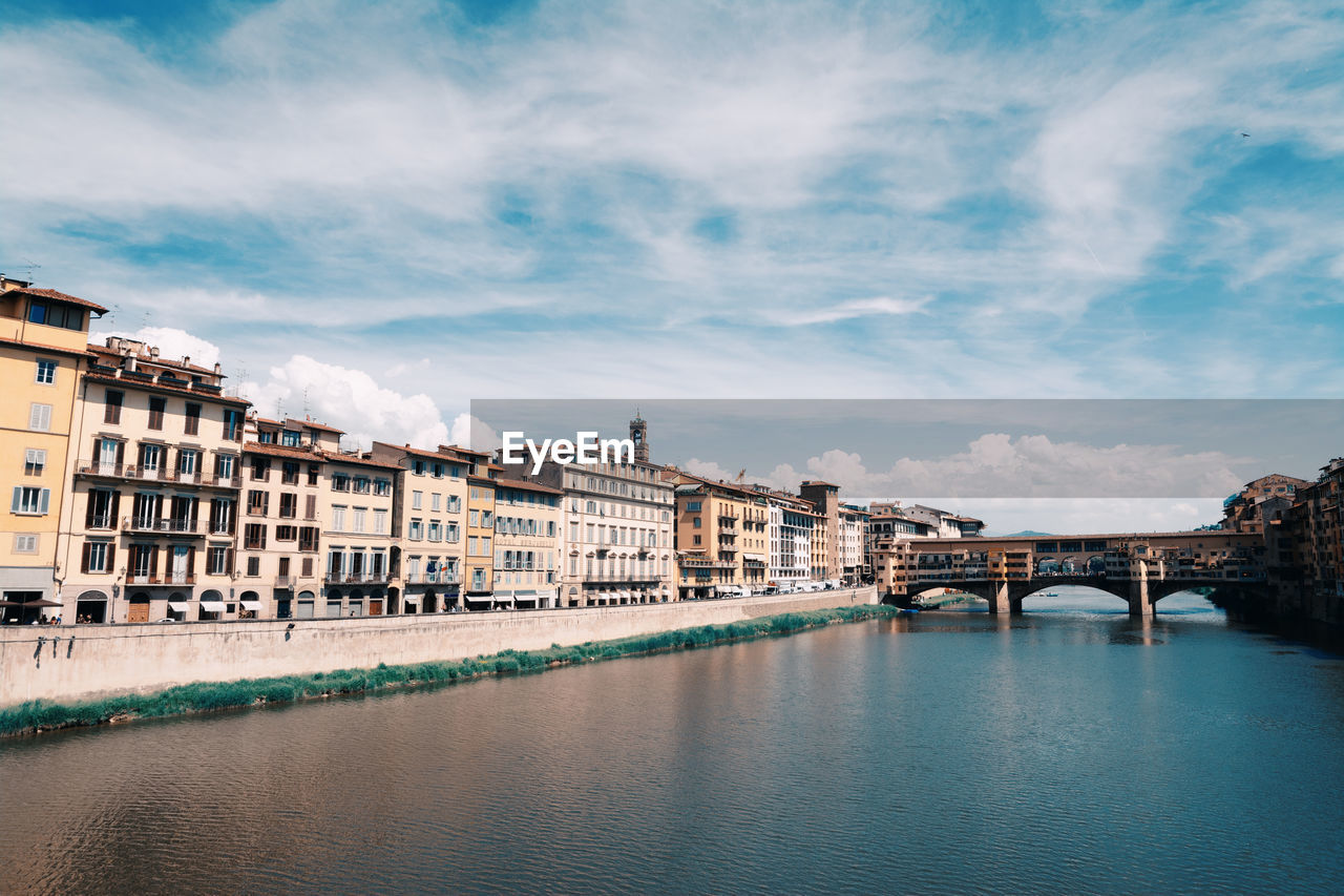 ARCH BRIDGE OVER RIVER BY BUILDINGS AGAINST SKY