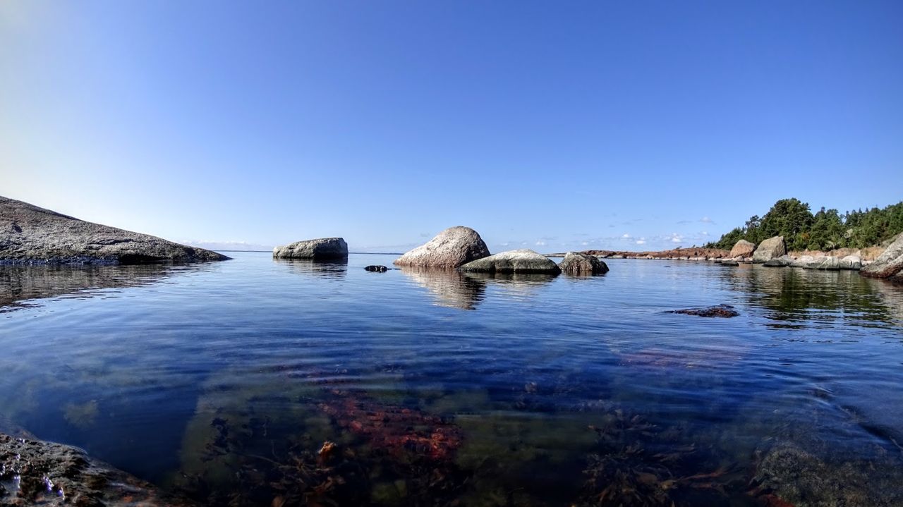 View of calm lake against clear blue sky