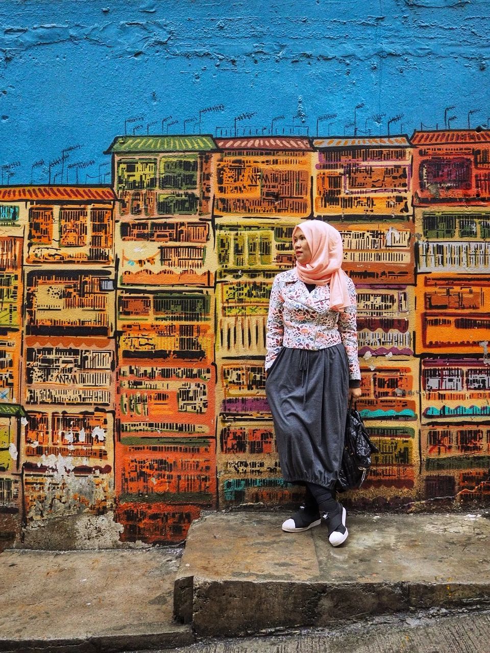 FULL LENGTH REAR VIEW OF WOMAN STANDING AGAINST GRAFFITI