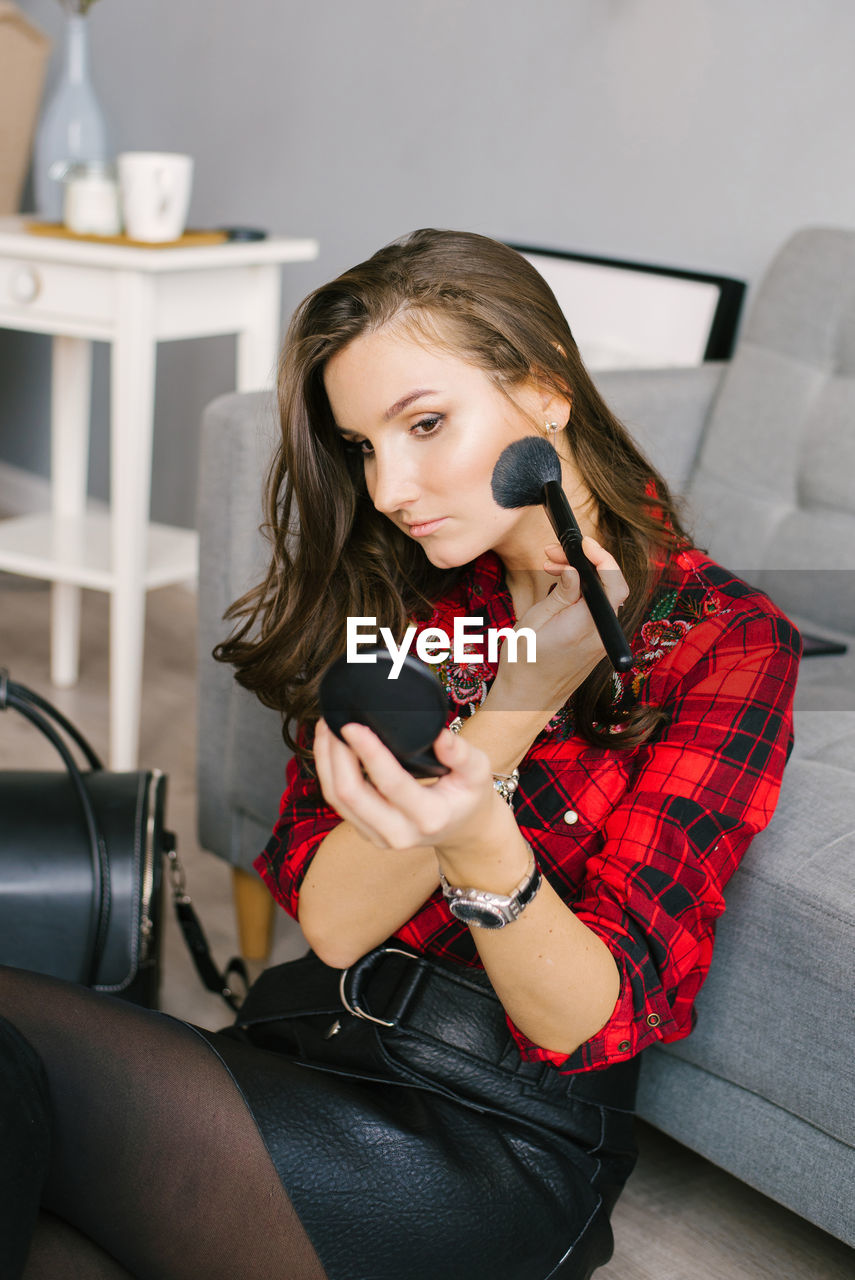 Young woman does her makeup, beautifully brush blush at home