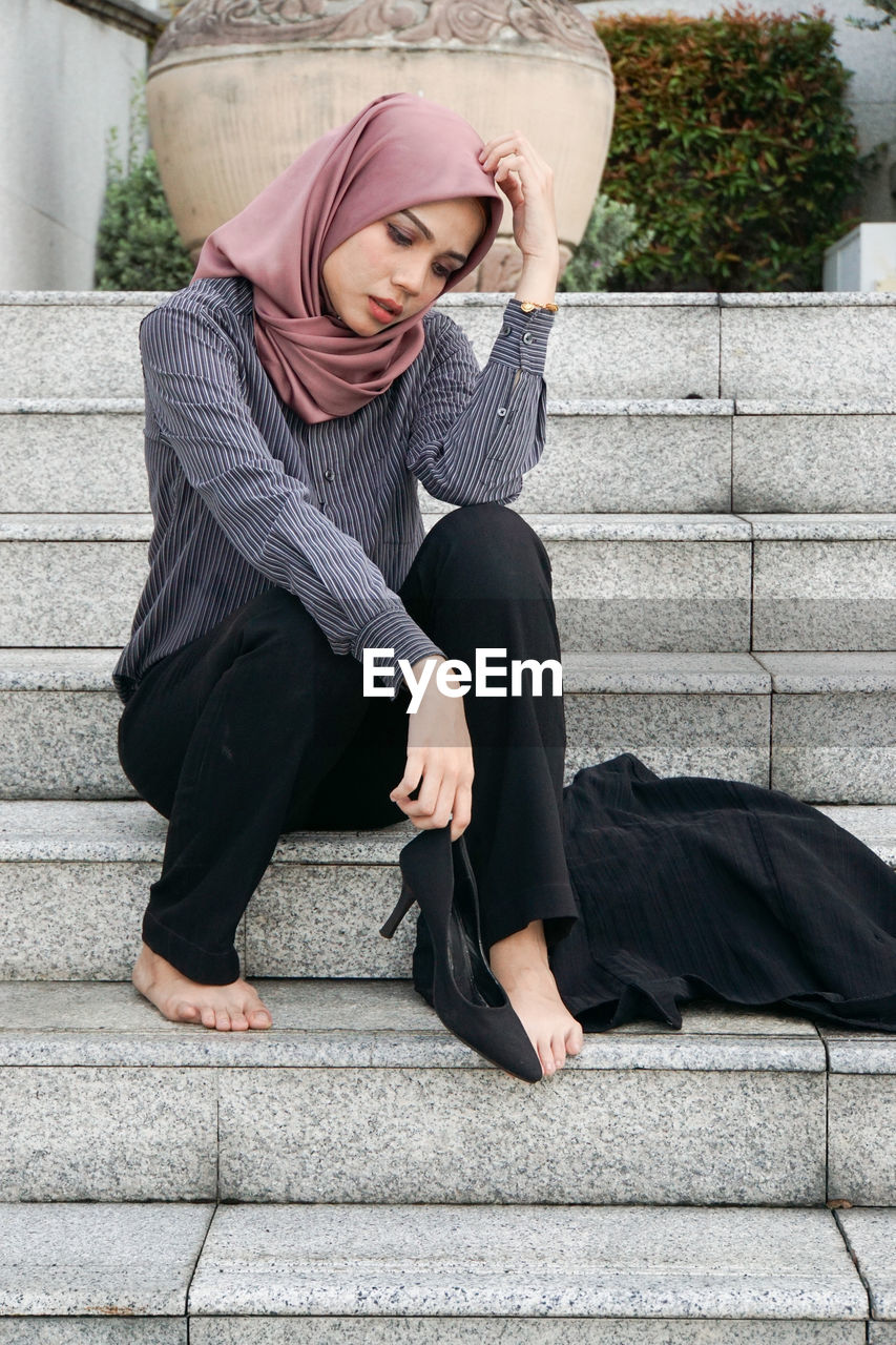 Full length of woman sitting on staircase