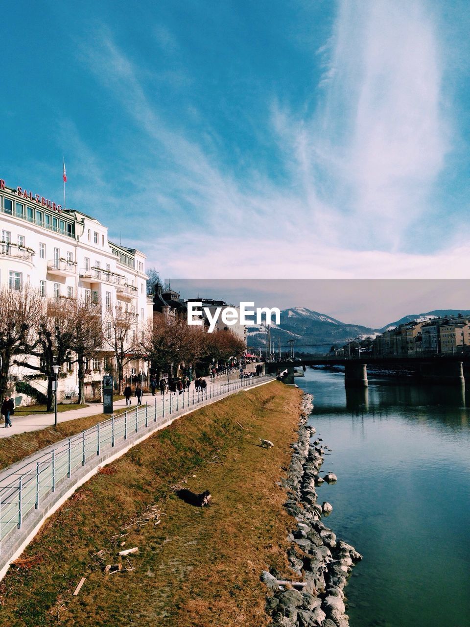 River by walkway against cloudy blue sky