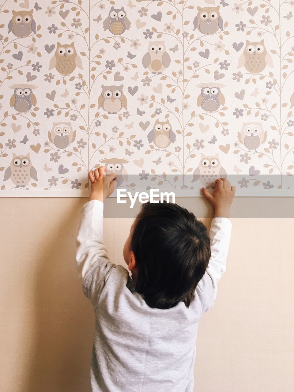 Rear view of child standing against patterned wall