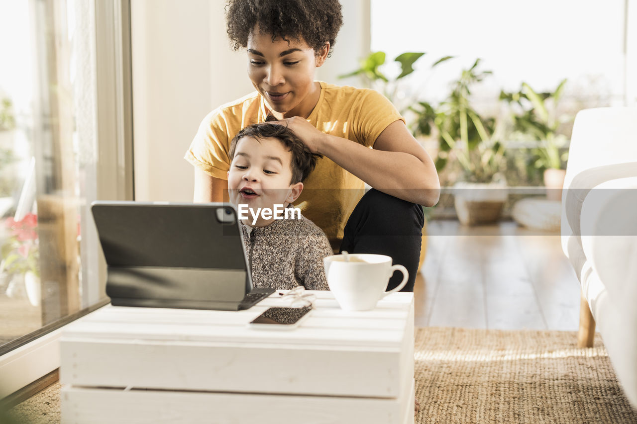 Mother and son using digital tablet while sitting at home