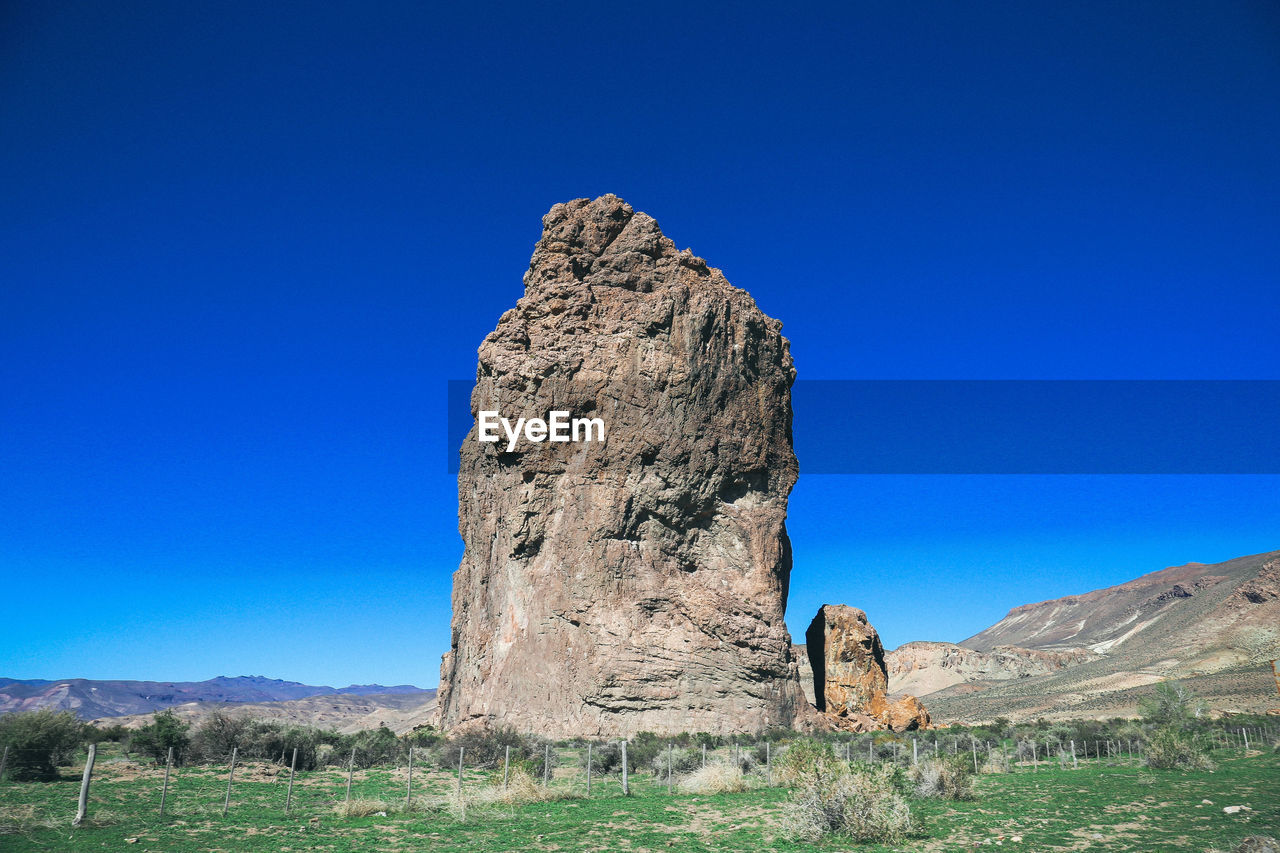 Stone structure on grassy mountain against clear blue sky