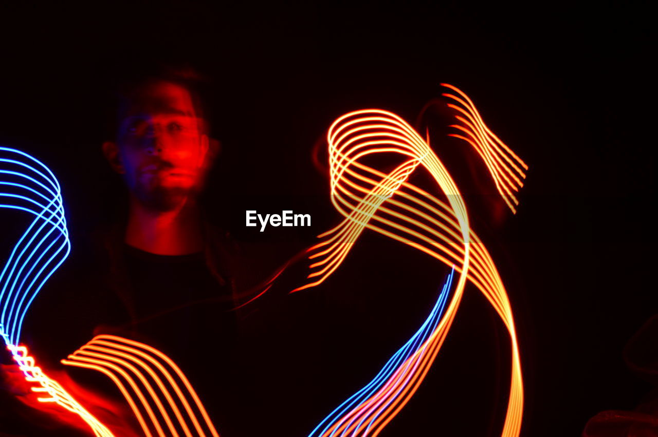 Man making colorful light painting in dark at night