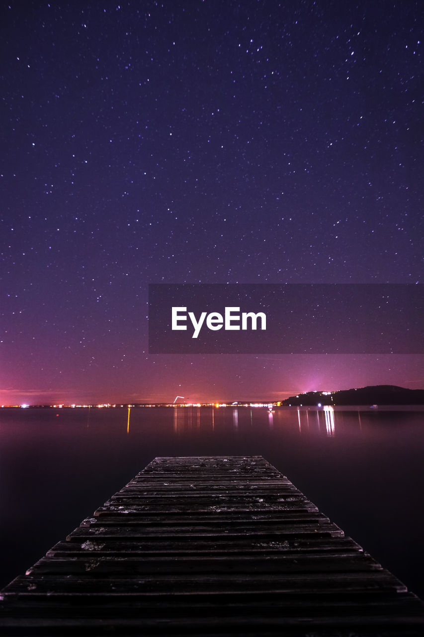 Scenic view of lake against clear sky at night with city lights in the background