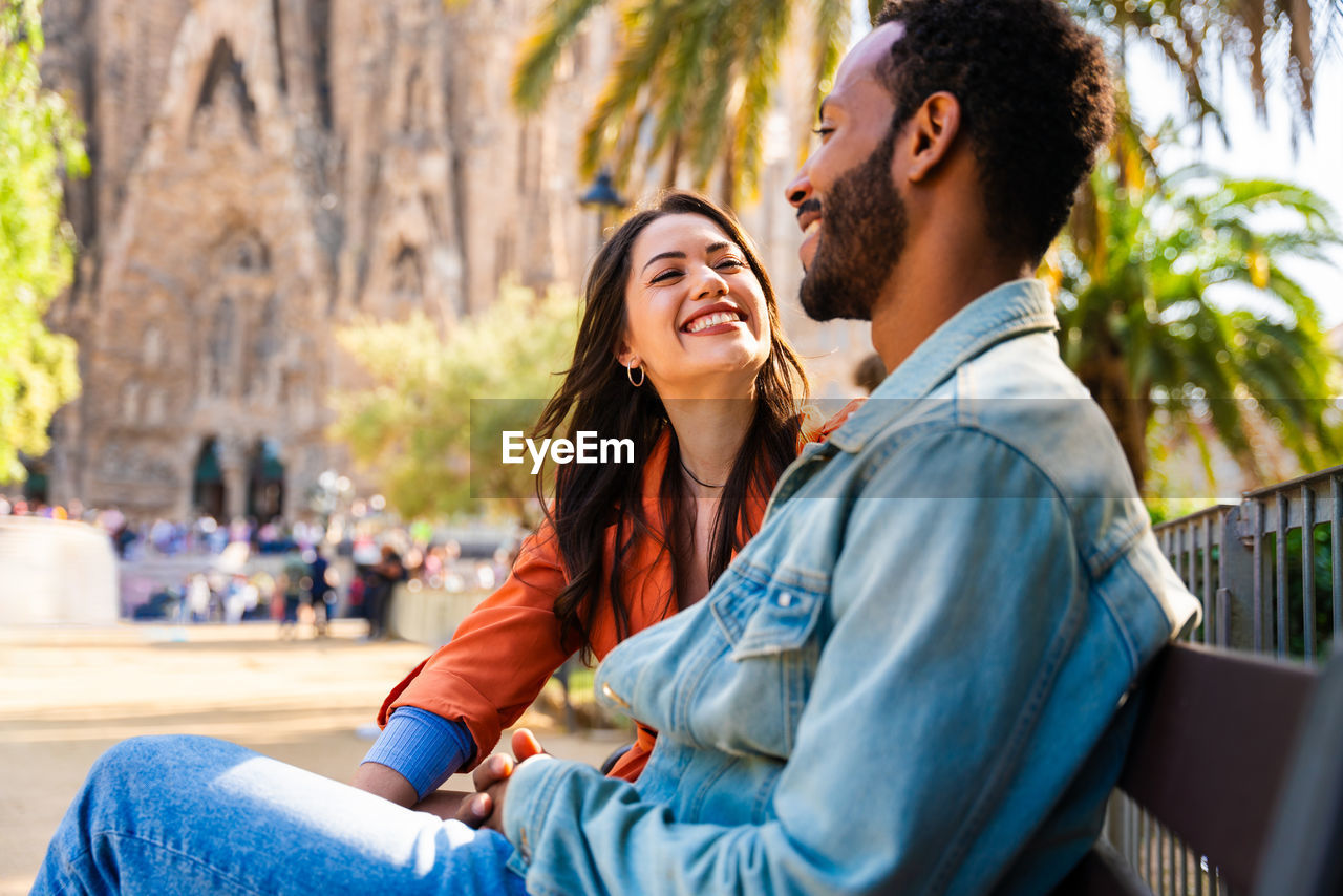 side view of woman using digital tablet while sitting in city