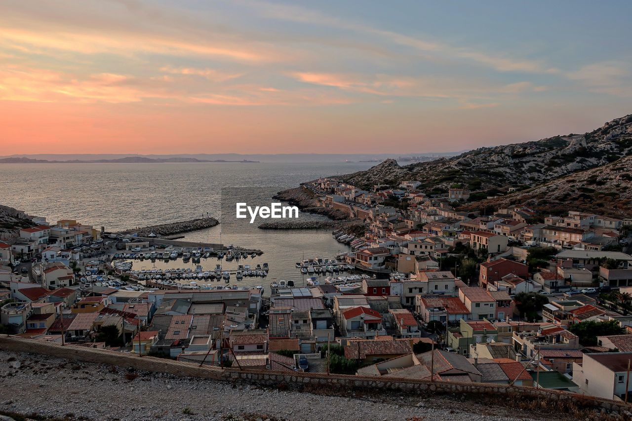 High angle view of townscape by sea against sky during sunset