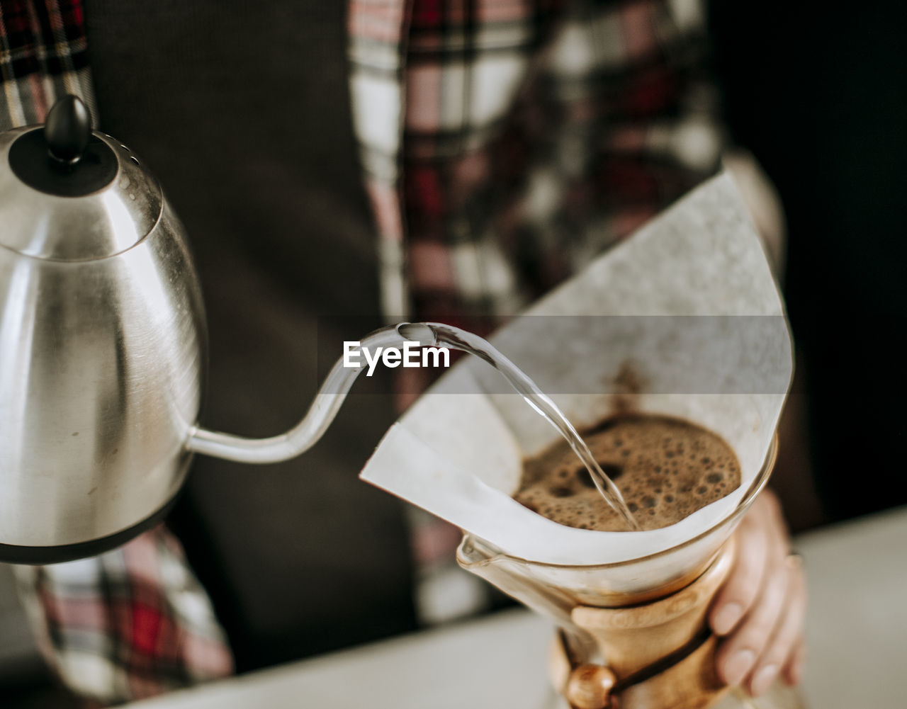 Hot water is poured from kettle to coffee grounds in a filter.