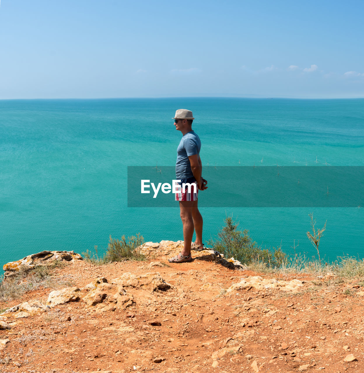 Adult man admires the panorama of the turquoise sea, summer in e