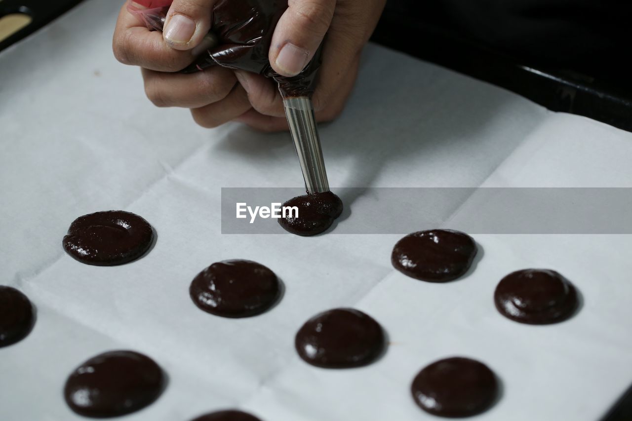 Cropped hands of person preparing food on wax paper