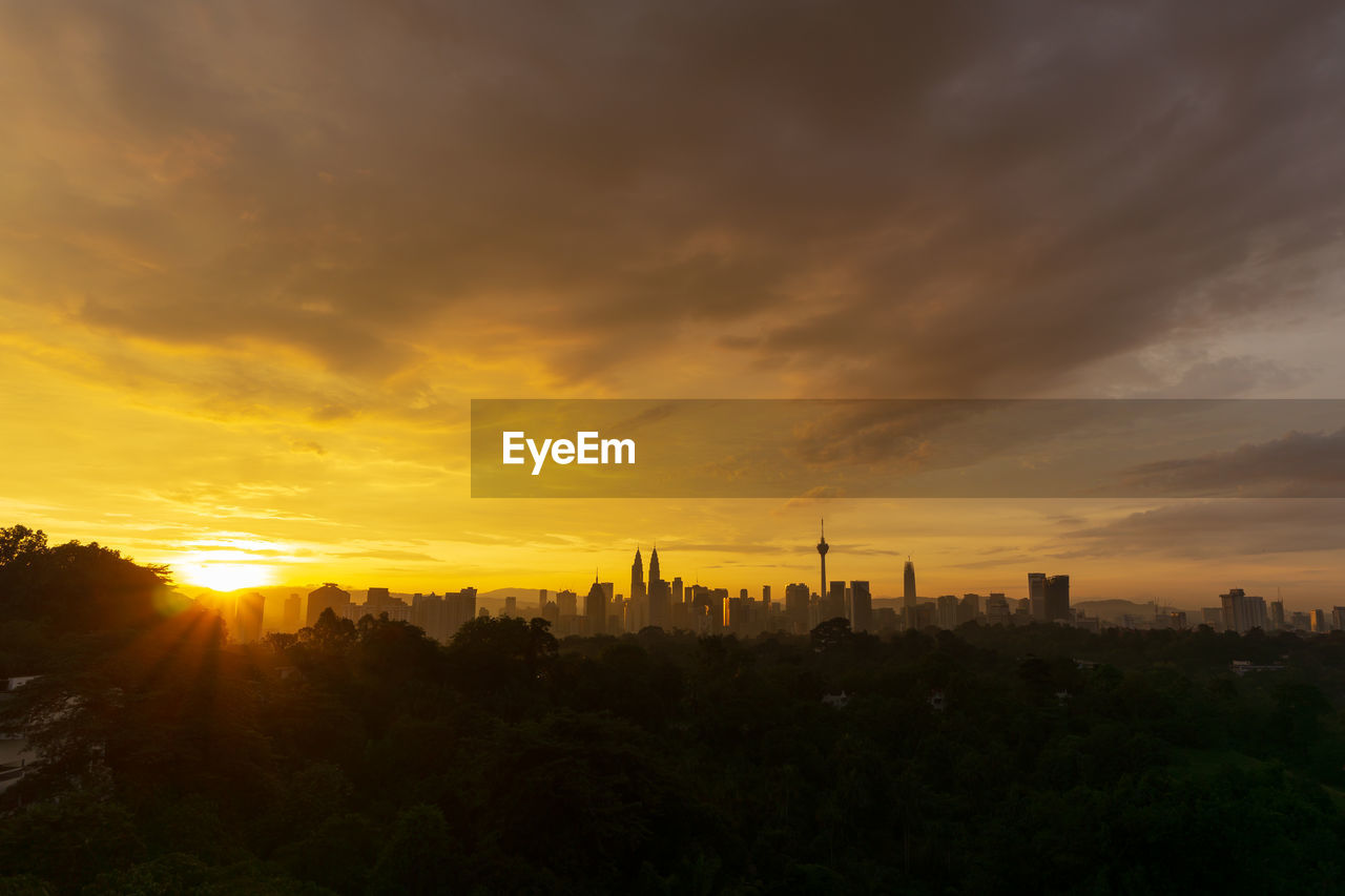 Silhouette of buildings against cloudy sky during sunset