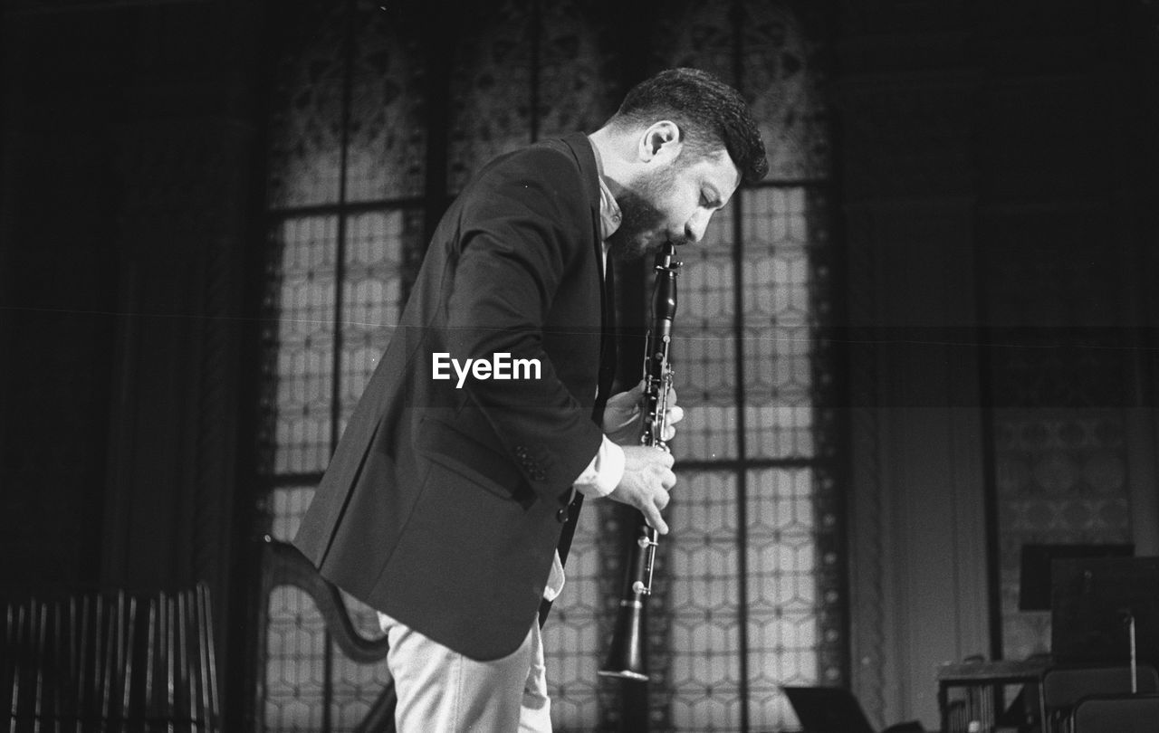 Man playing clarinet while standing at studio