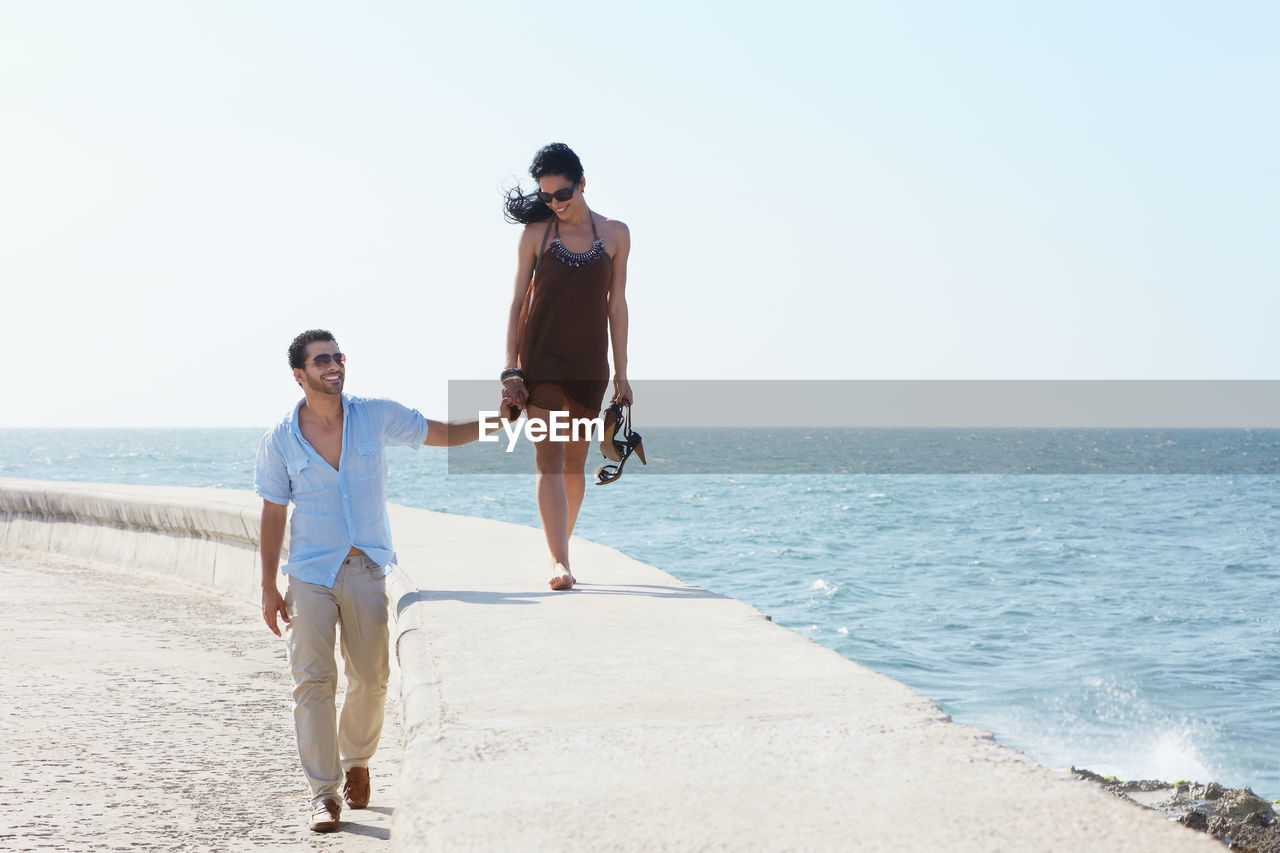 FULL LENGTH OF WOMEN ON BEACH AGAINST CLEAR SKY