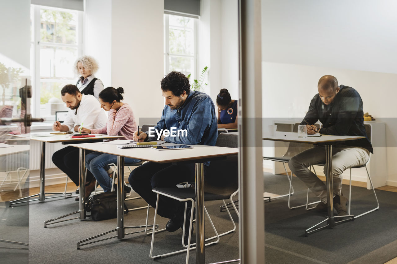 Teacher looking at students writing in language class