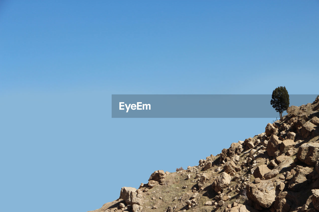 Low angle view of rock formation against clear blue sky