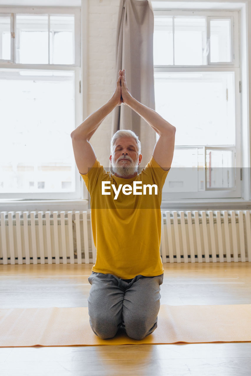 Man with gray hair meditates and does breathing exercises. sports fitness and physical exercises 