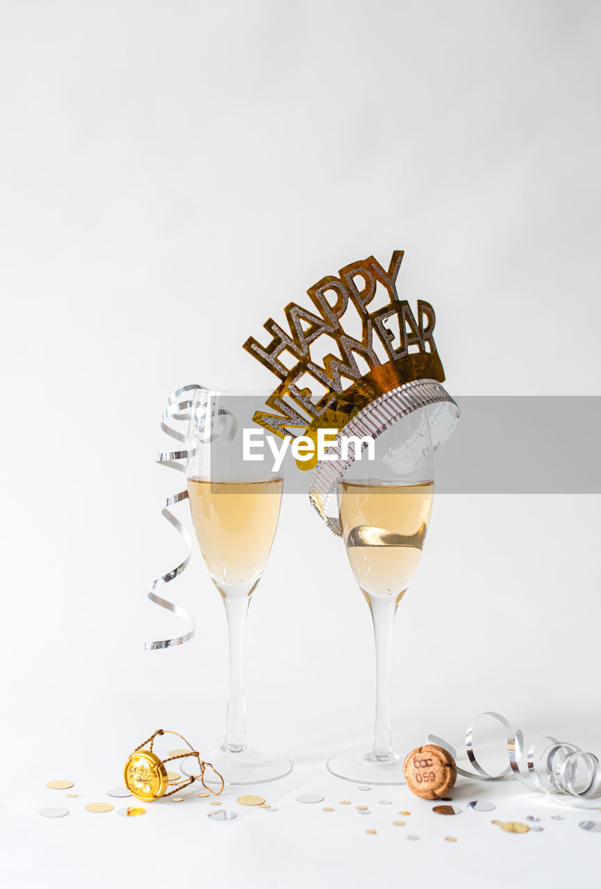 Glasses of champagne and happy new year hat on white background.