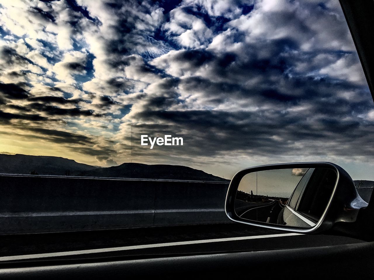 REFLECTION OF CLOUDY SKY ON SIDE-VIEW MIRROR