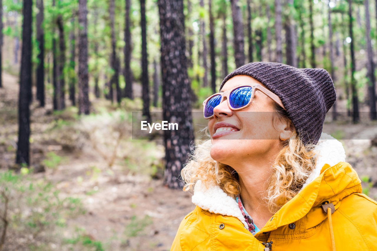 Woman wearing sunglasses in forest against trees