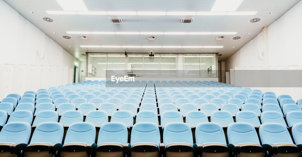 auditorium, seat, indoors, conference hall, chair, in a row, room, empty, architecture, convention center, no people, sport venue, large group of objects, education, order, school, absence, building, function hall