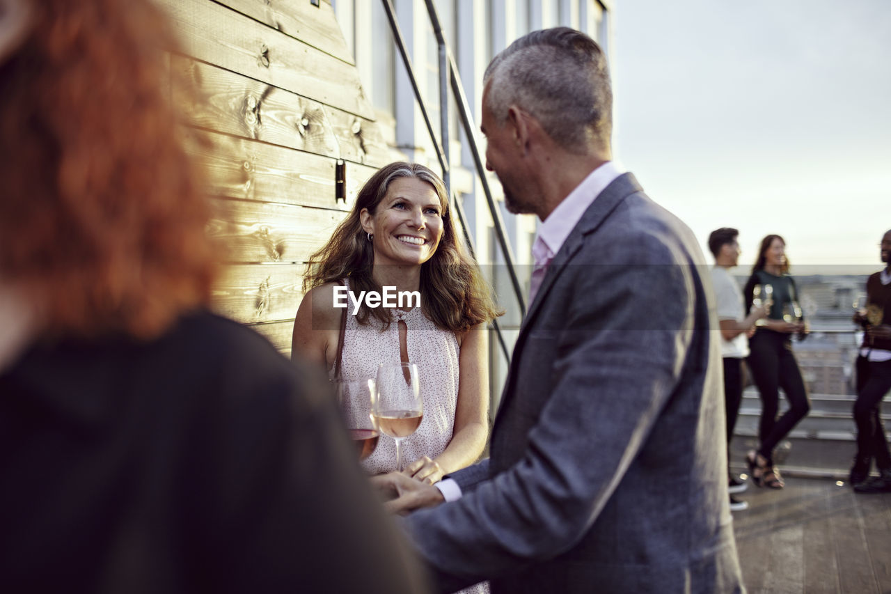 Smiling businesswoman talking with coworkers in party on terrace