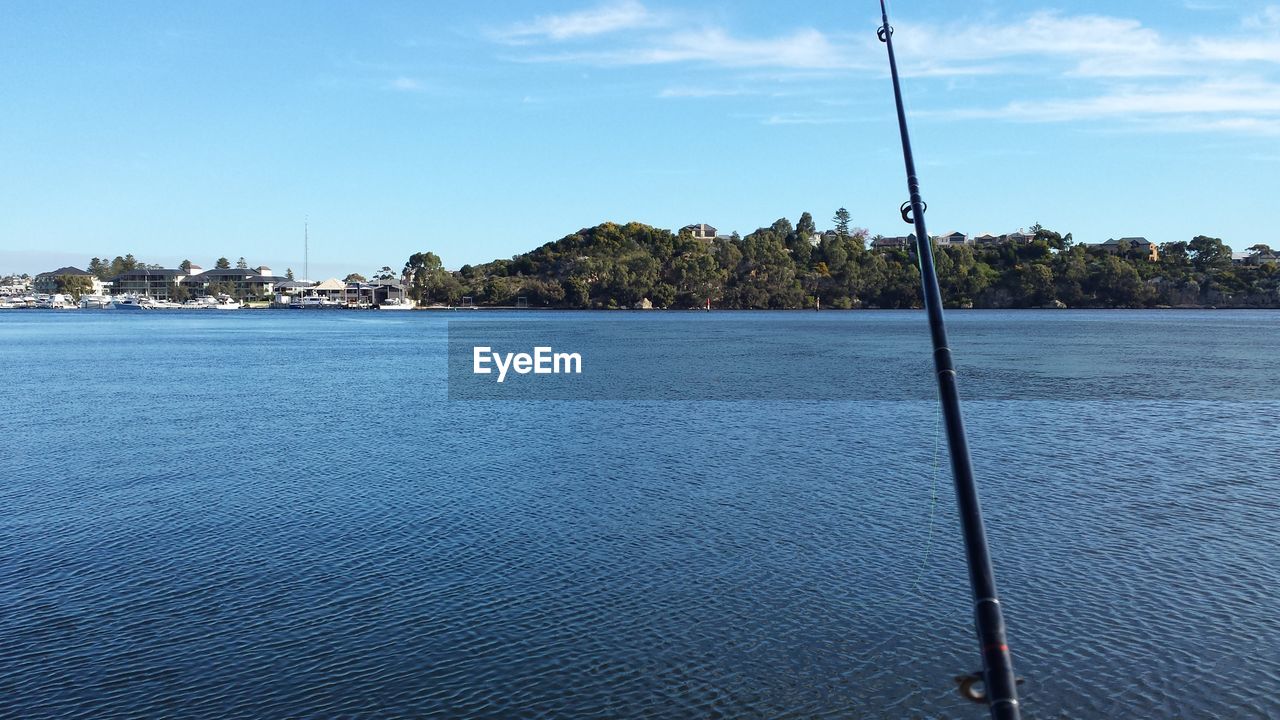 Fishing rod at lake against sky